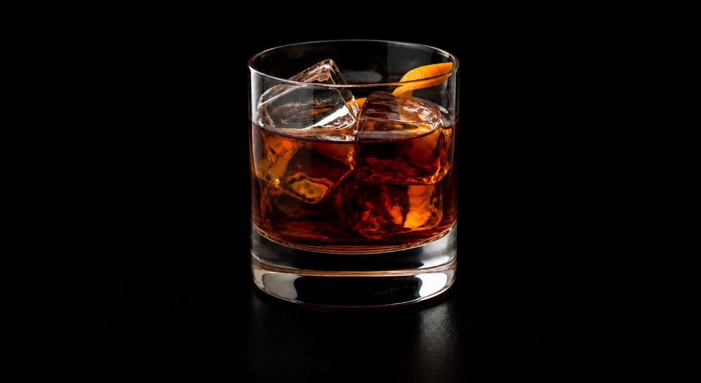 Black Apple Old-Fashioned cocktail on a dark studio background