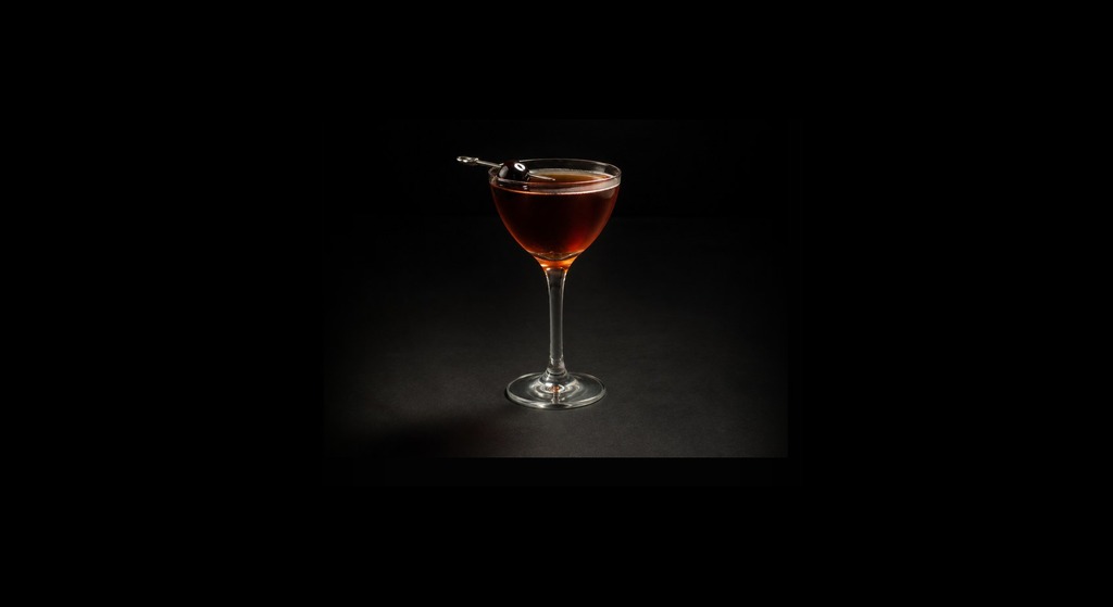 Black Manhattan cocktail on a dark studio background