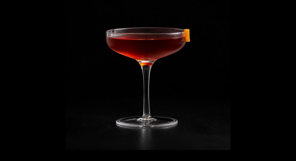 Sips Adonis cocktail on a dark studio background