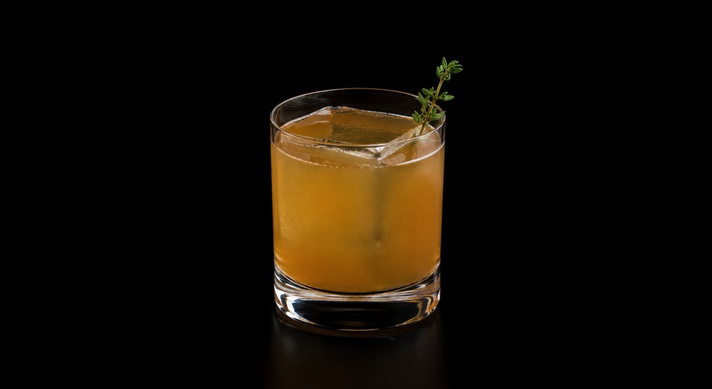 Thyme Will Tell Sour cocktail on a dark studio background